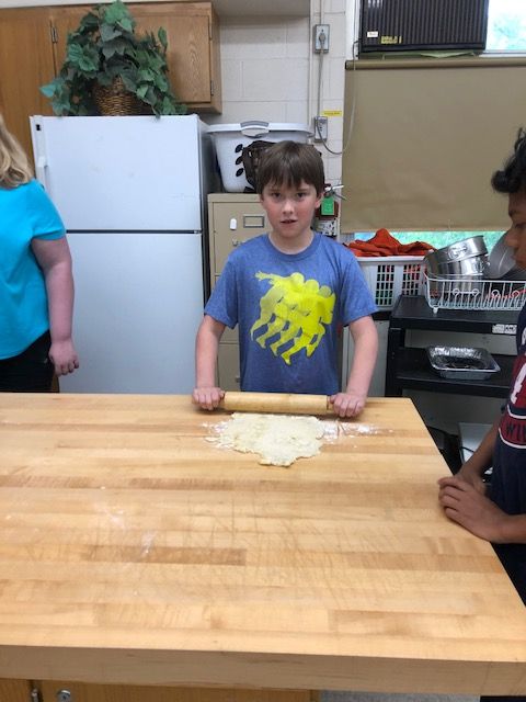 Student rolling pizza dough.