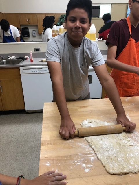 Student rolling pizza dough.
