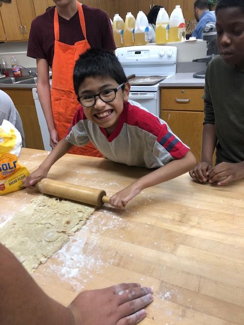 Student rolling pizza dough.
