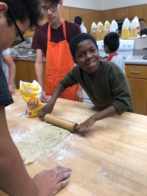 Student rolling pizza dough.