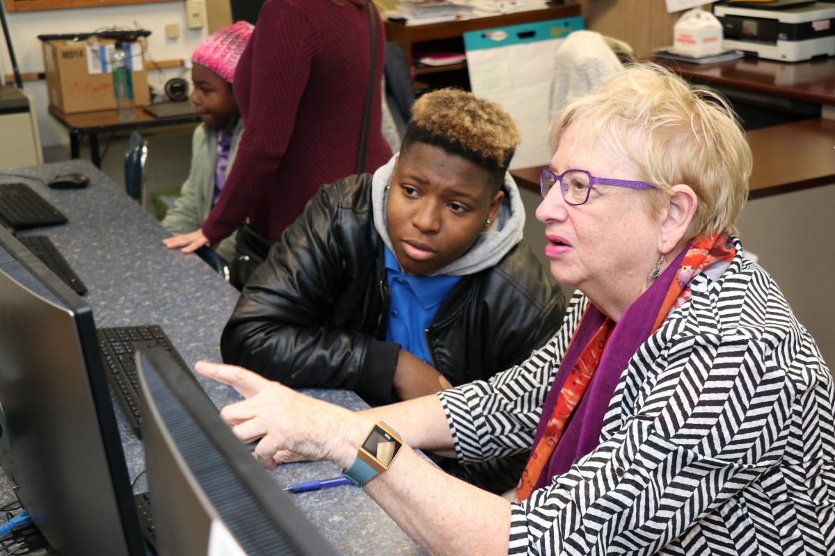 High school scholar helps community member with coding activity.