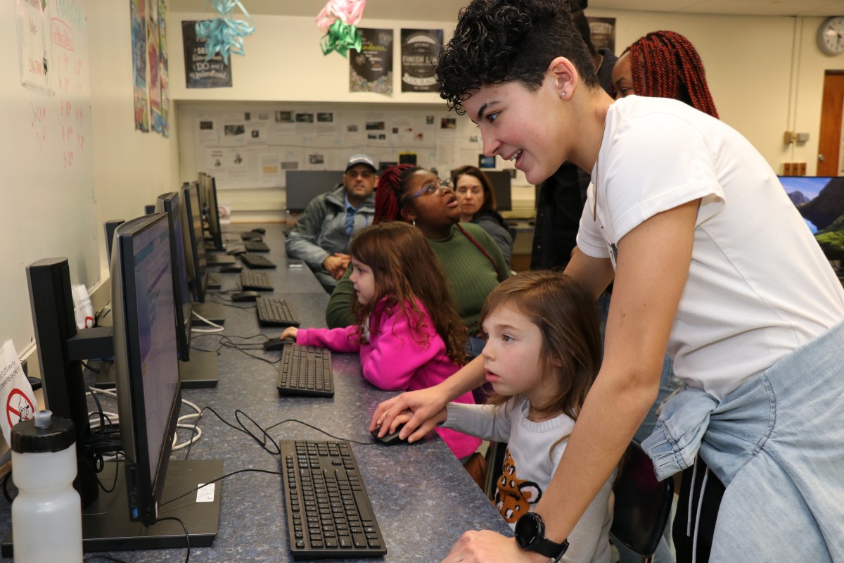 High school scholar helps younger student with coding activity.