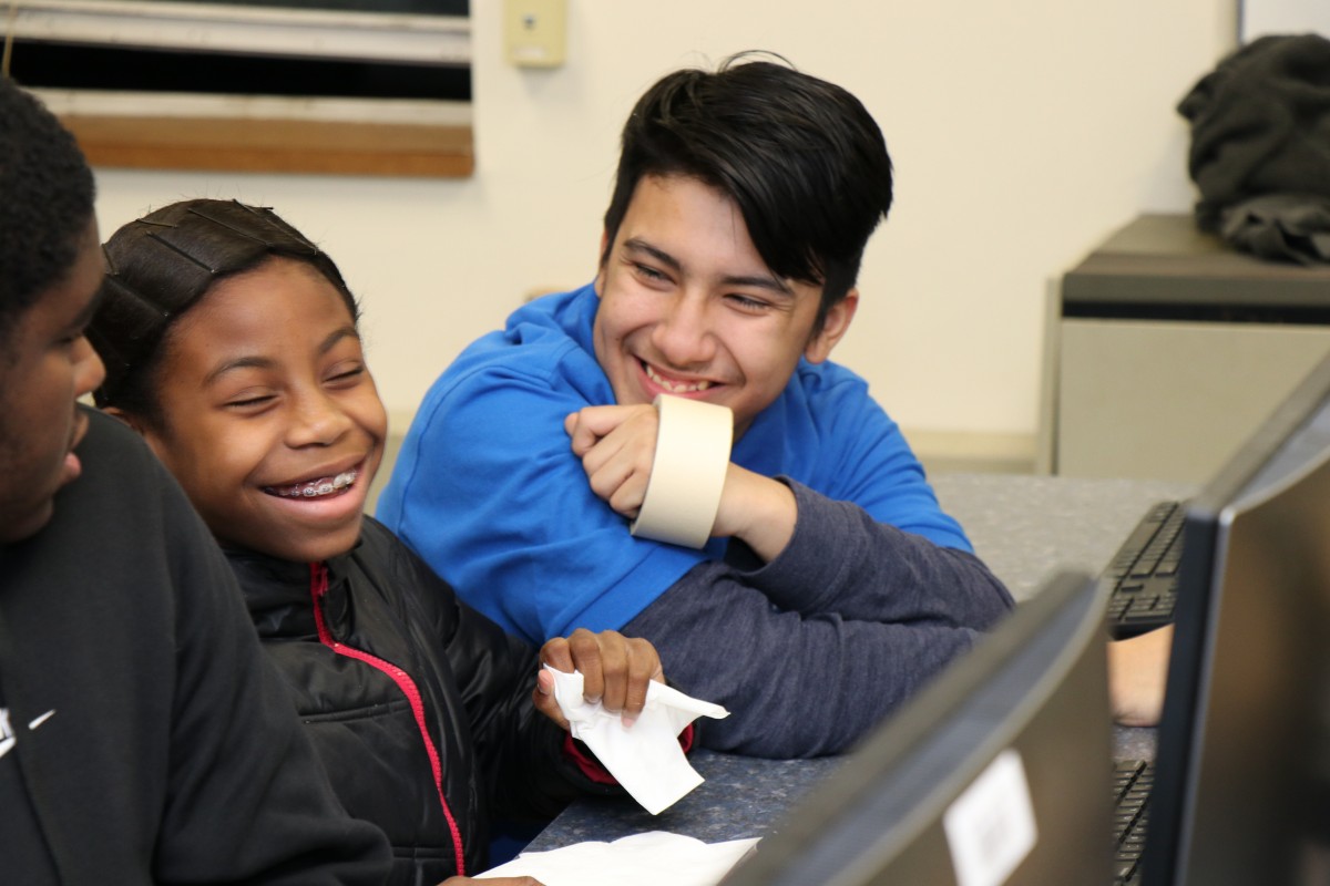 High school scholar helps younger student with coding activity.