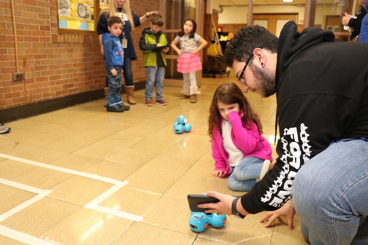 High school scholar helps younger student with coding activity.