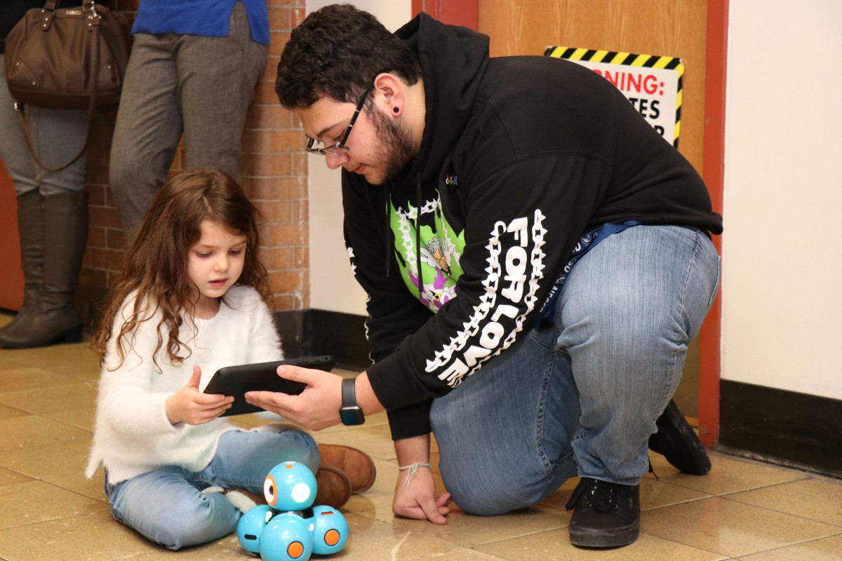 High school scholar helps younger student with coding activity.