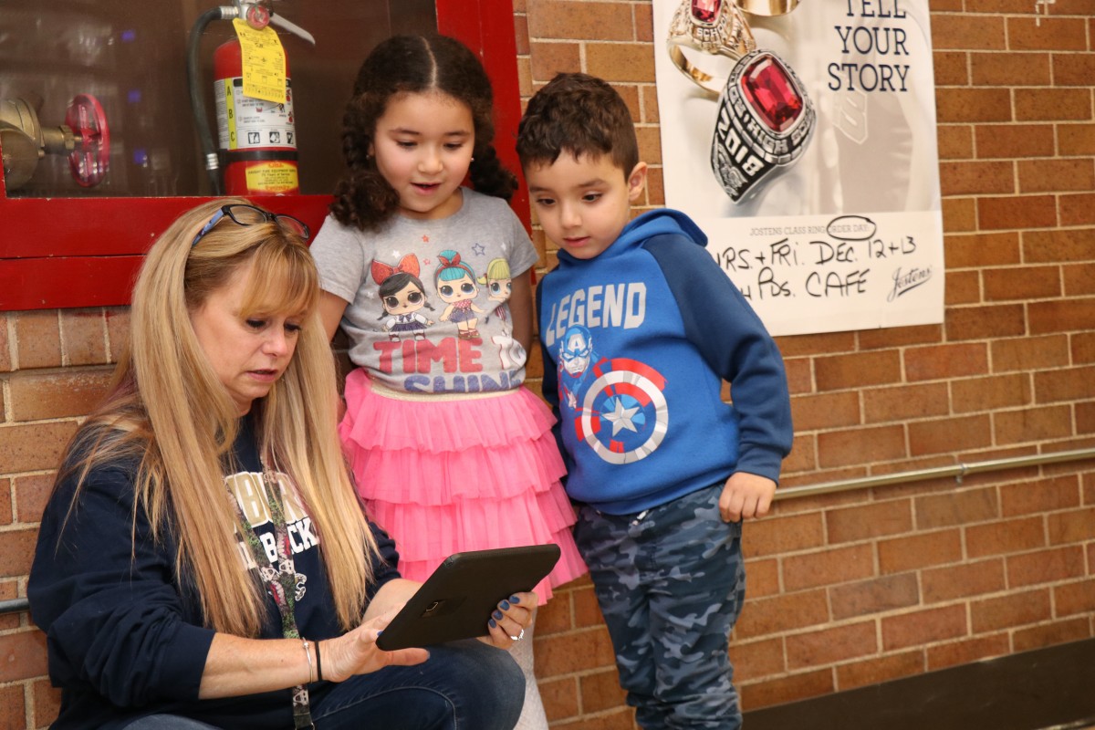 High school scholar helps younger student with coding activity.