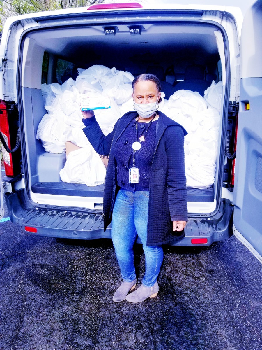 Ms. Kori Rogers, McKinney-Vento Homeless Liaison after loading the CHI van with Food Backpack supplies, holding a box of mask donated by the Rotary Club.