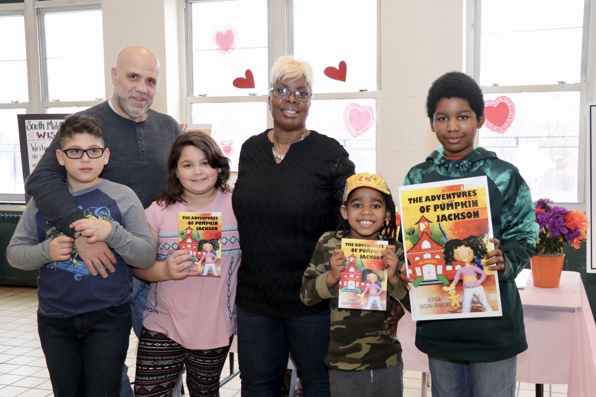 Author, Ms. Glenda Faison-Crawford poses with students holding her book