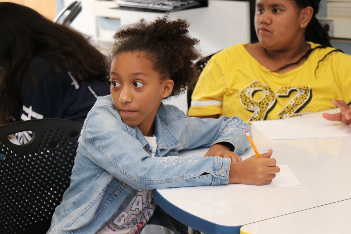 Students try drawing characters using a handful of shapes, under the direction of the presenter.