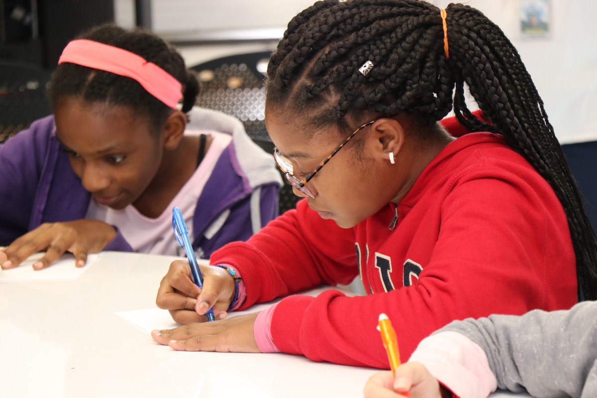 Students try drawing characters using a handful of shapes, under the direction of the presenter.