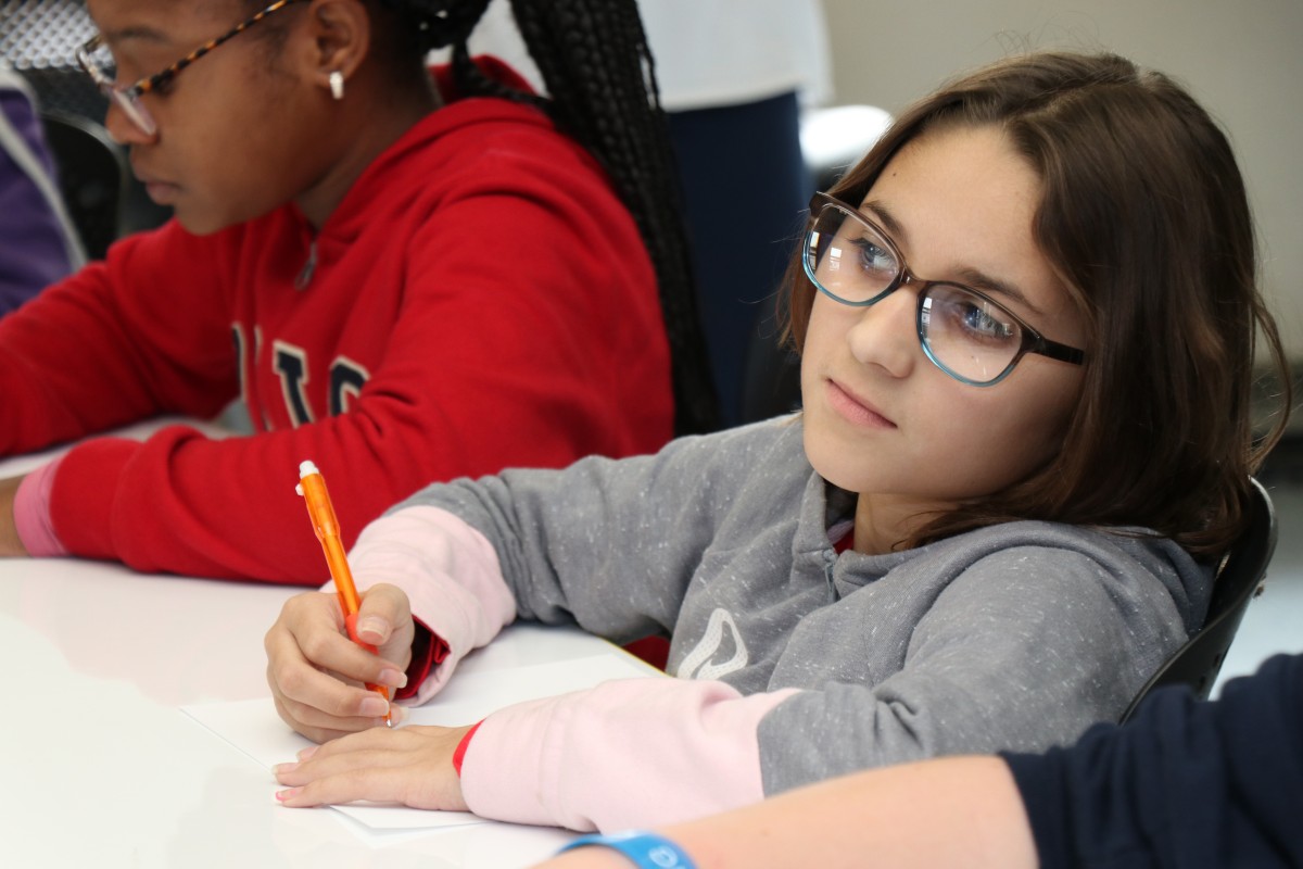 Students try drawing characters using a handful of shapes, under the direction of the presenter.