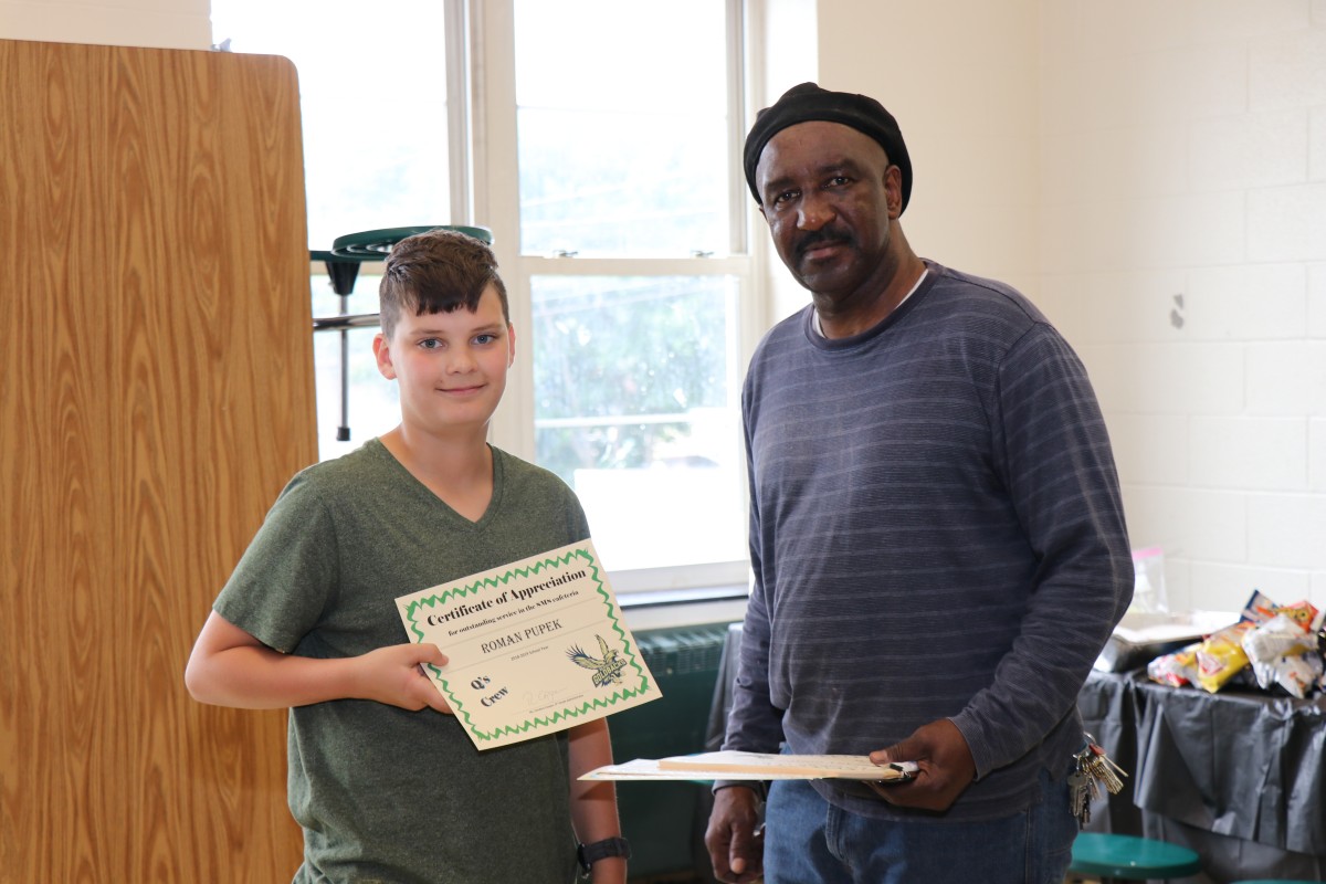 Student receives certificate from Mr. Q.