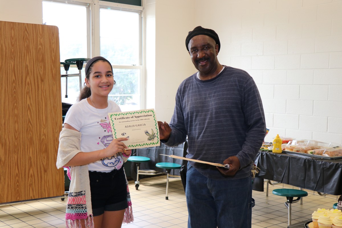 Student receives certificate from Mr. Q.