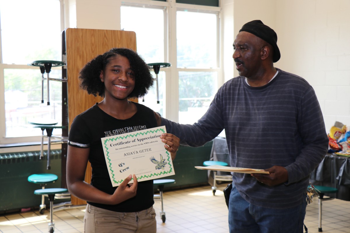 Student receives certificate from Mr. Q.
