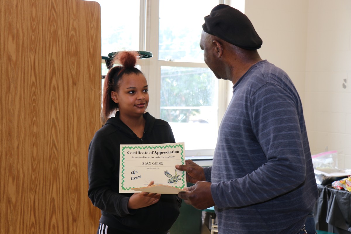 Student receives certificate from Mr. Q.