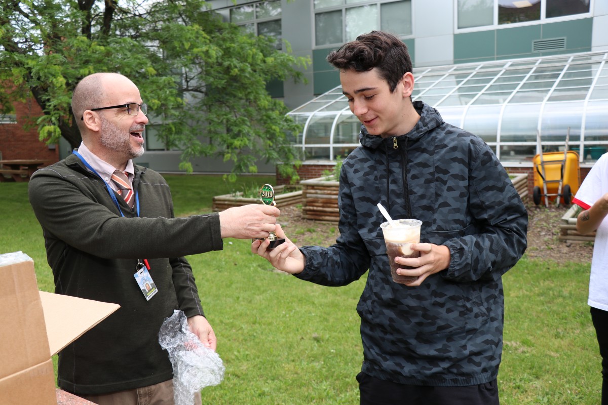 Mr. Hickey hands a trophy to a student.