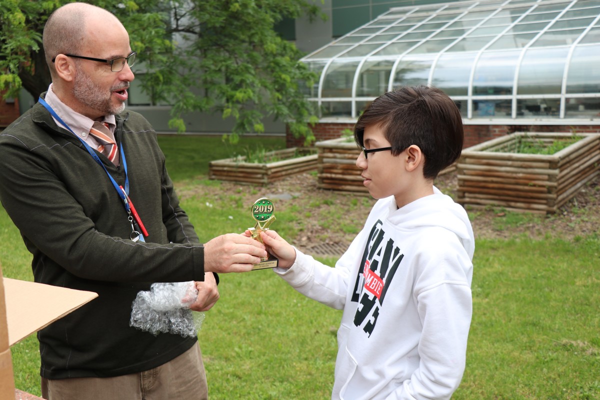 Mr. Hickey hands a trophy to a student.