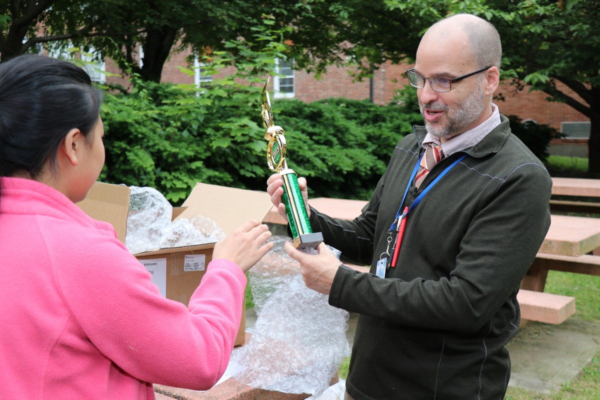 Mr. Hickey hands a trophy to a student.