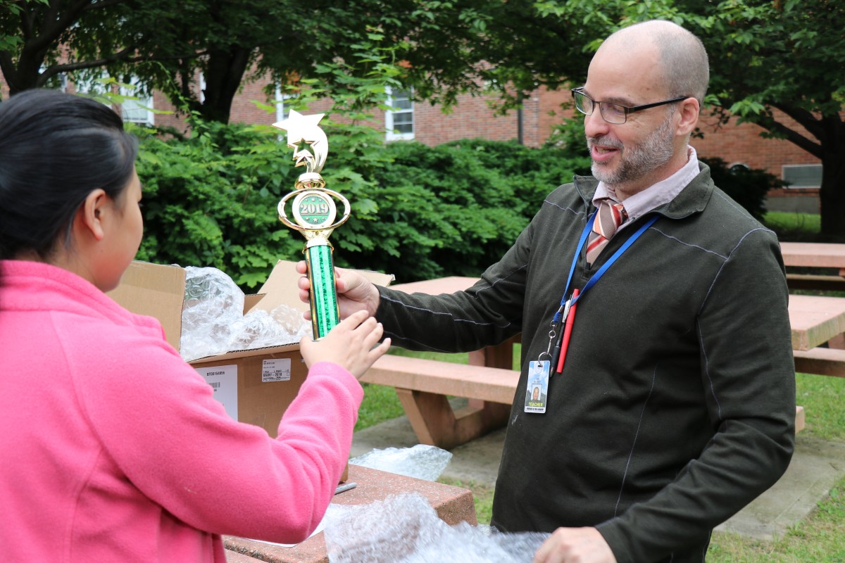 Mr. Hickey hands a trophy to a student.