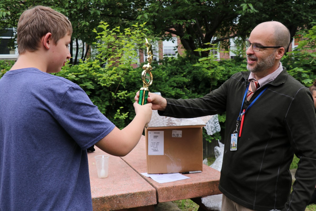 Mr. Hickey hands a trophy to a student.