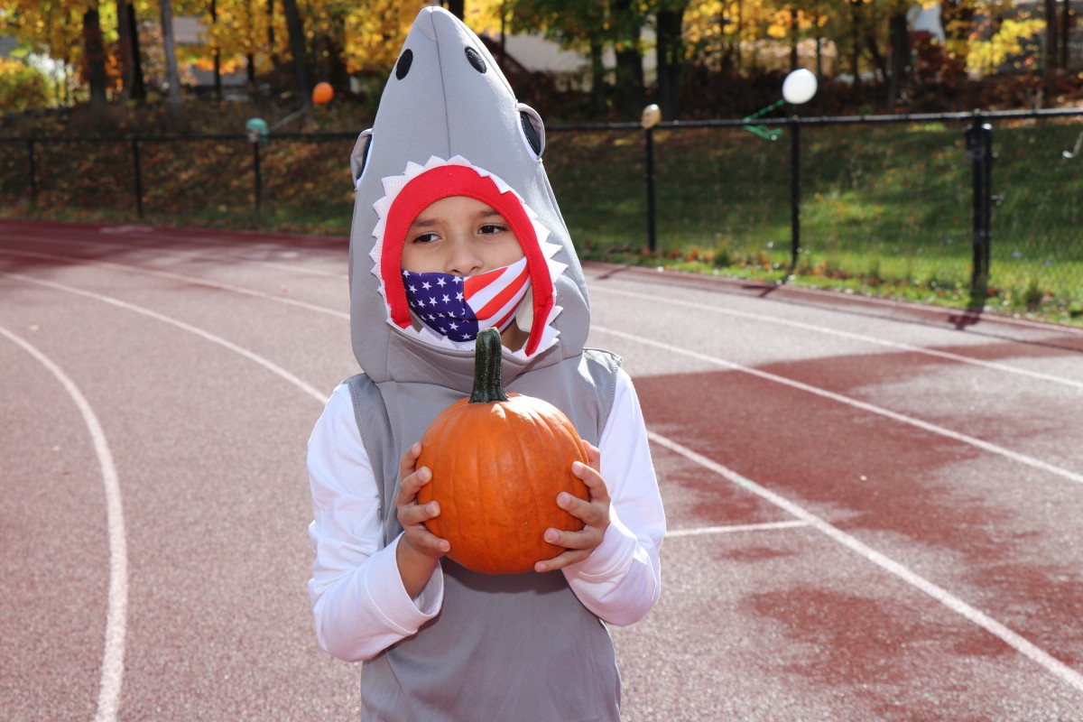 Student poses with pumpkin.