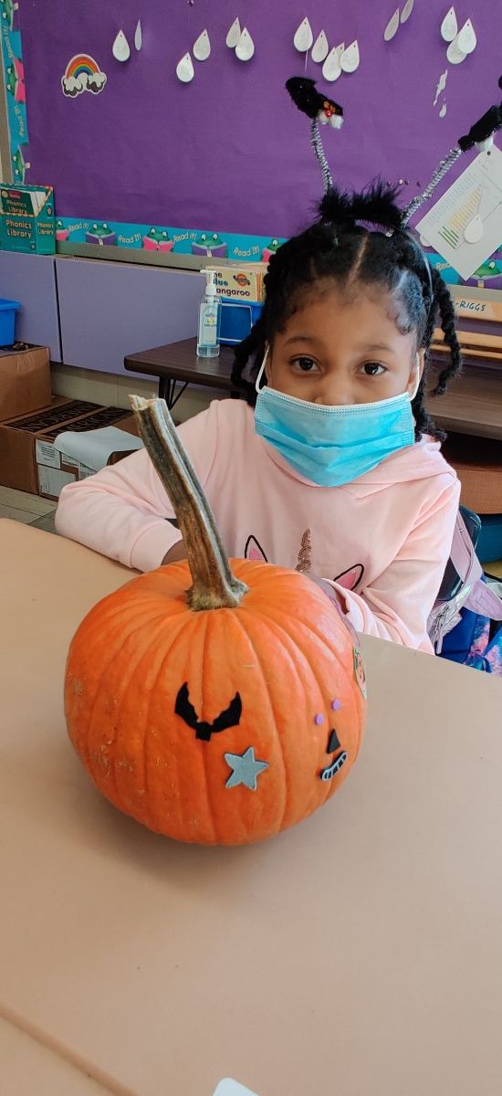 Student poses with pumpkin.