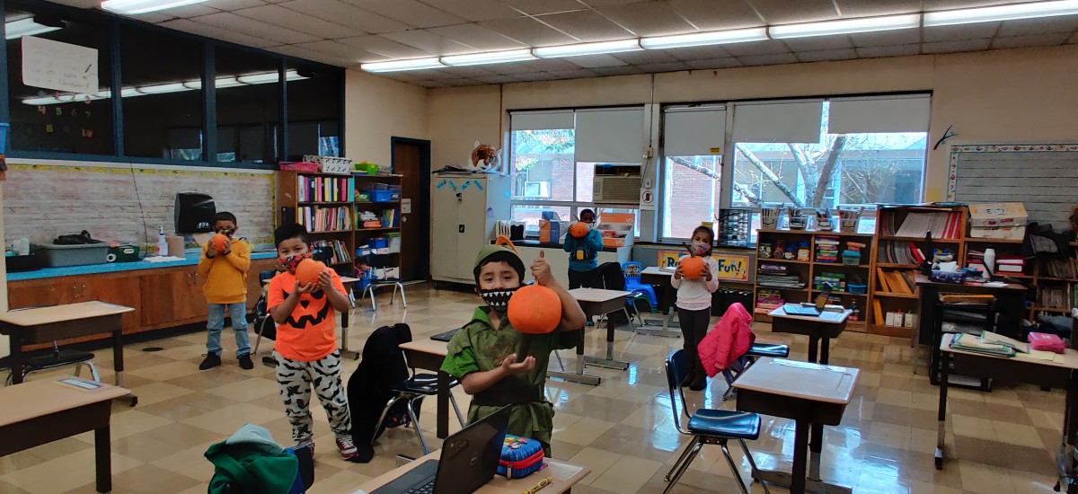 Students decorating pumpkins in classroom.