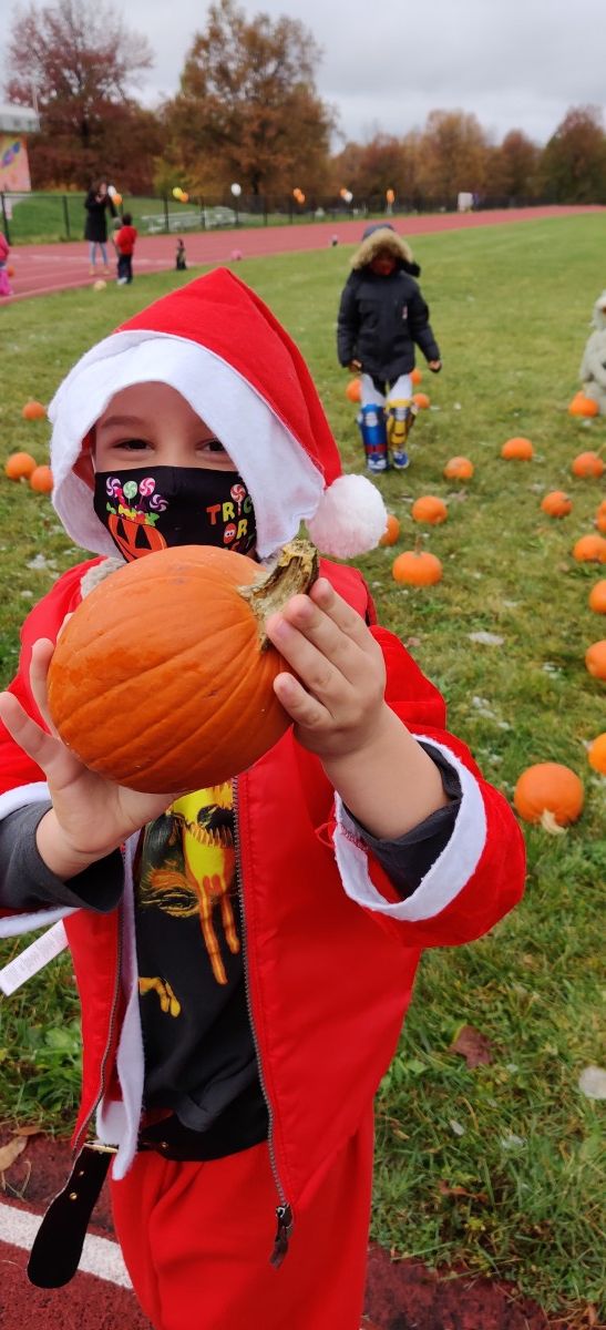 Student picks pumpkin from pumpkin patch.