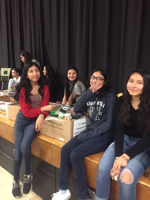 Students sit on stage with donations.