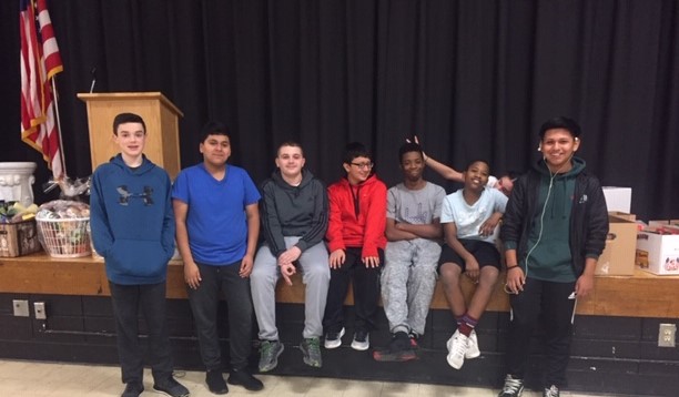 Students sit on stage with donations.