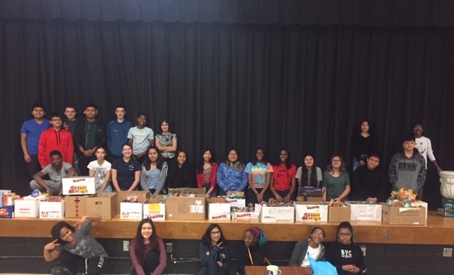 Students sit on stage with donations.