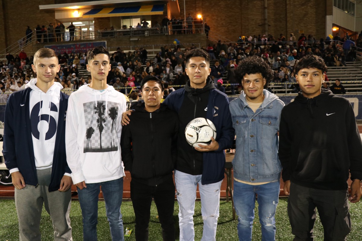 Athletes stand with the signed ball.