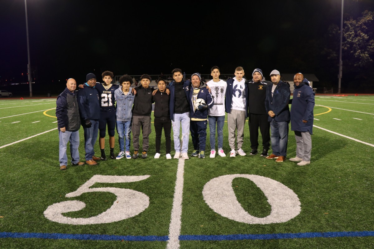 Coaches Iorlano and Matthews stand with players and Superintendent Dr. Roberto Padilla, Board of Education member, Mr. Philip Howard, Athletic Director, Mr. Edgar Glascott, and Director of Physical Education, Mr. Howie Harrison on the field.