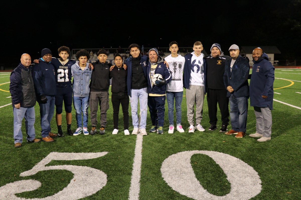 Coaches Iorlano and Matthews stand with players and Superintendent Dr. Roberto Padilla, Board of Education member, Mr. Philip Howard, Athletic Director, Mr. Edgar Glascott, and Director of Physical Education, Mr. Howie Harrison on the field.