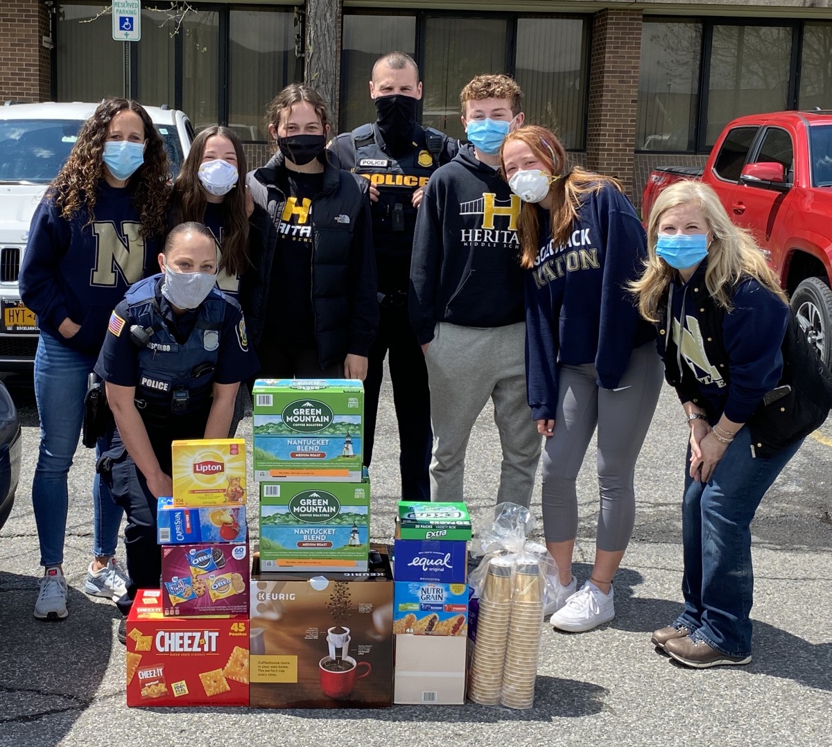 Heritage Middle School volunteers and a police officer pose with donated items.