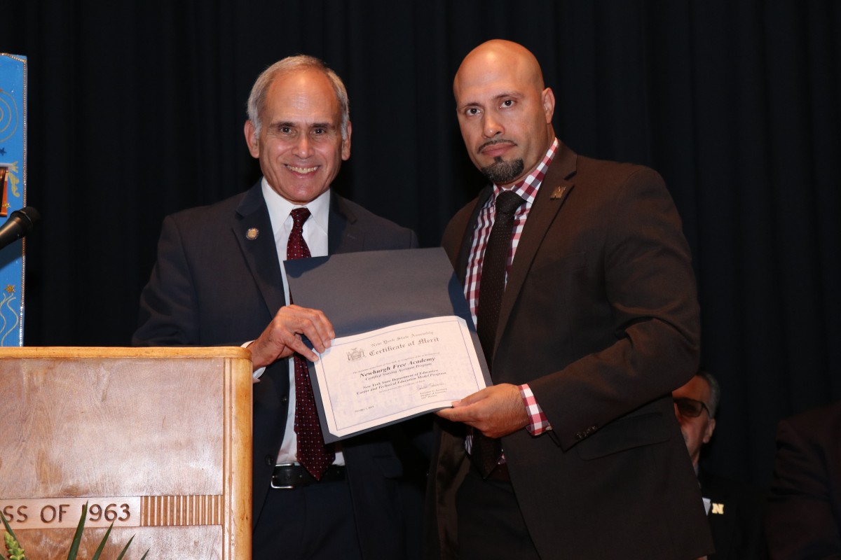 Assemblyman Jonathan Jacobson hands Superintendent Dr. Roberto Padilla a certificate.