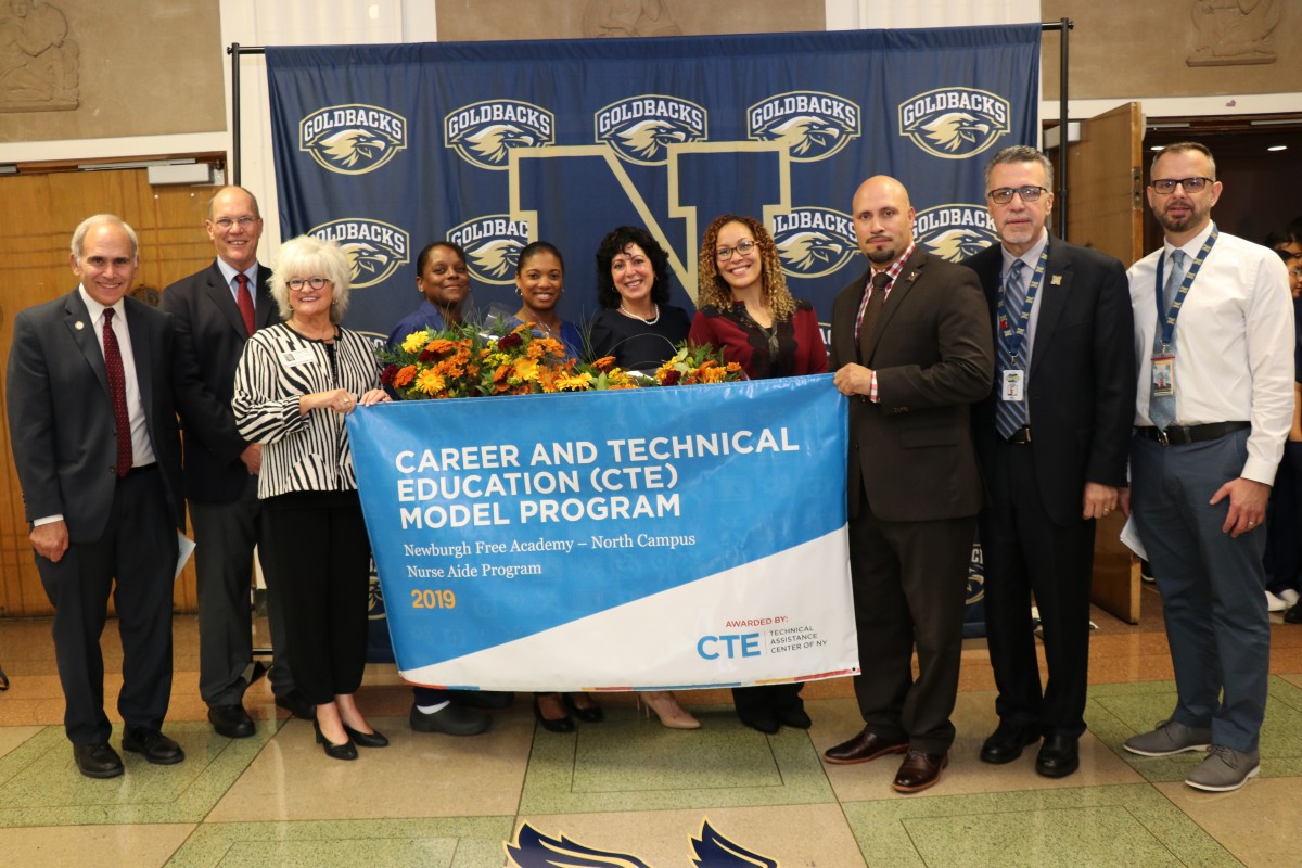 CNA teachers pose for a photo with Assemblyman Jonathan Jacobson, representatives from CTE TAC, Dr. Roberto Padilla, Mr. Matteo Doddo, and Mr. John Etri.