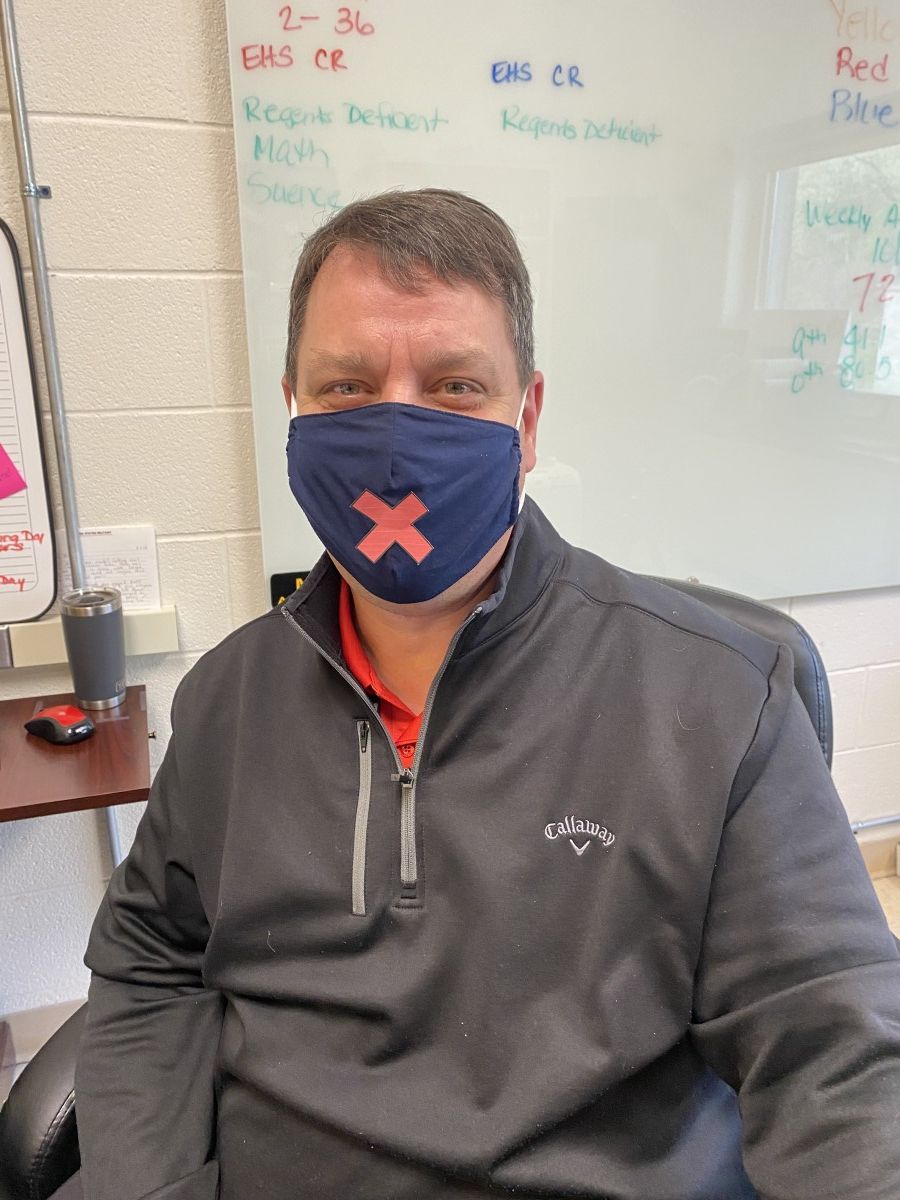 Mr. Robert Shust poses for a photo wearing a mask with an X on it, symbolizing the silence.