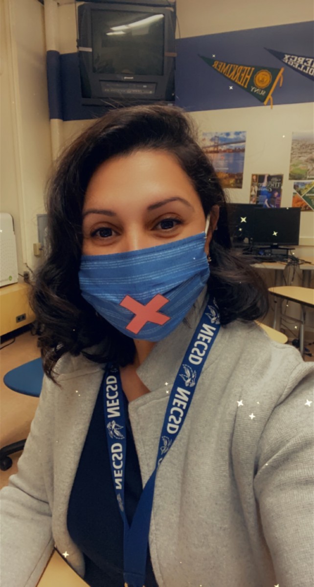 Mrs. Melanie Roman poses for a photo wearing a mask with an X on it, symbolizing the silence.