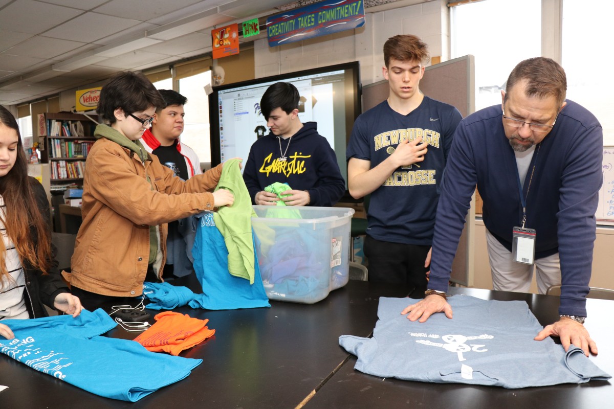 Students looking at shirts and their design from previous events.