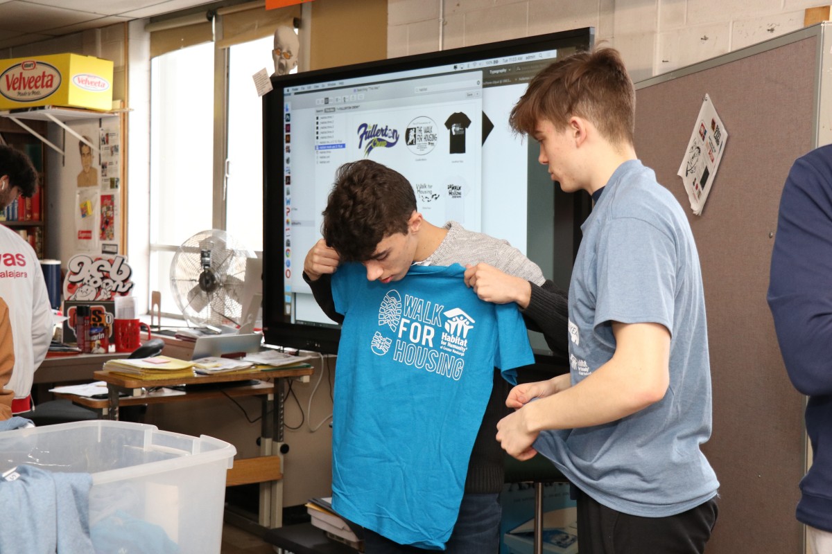 Students looking at shirts and their design from previous events.