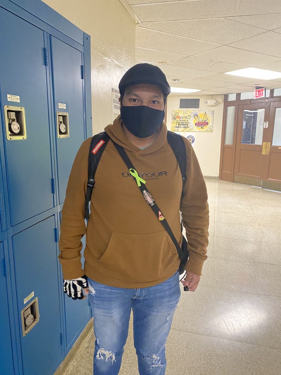 Student poses for a photo while wearing green ribbon to symbolize Mental Health Awareness Month.