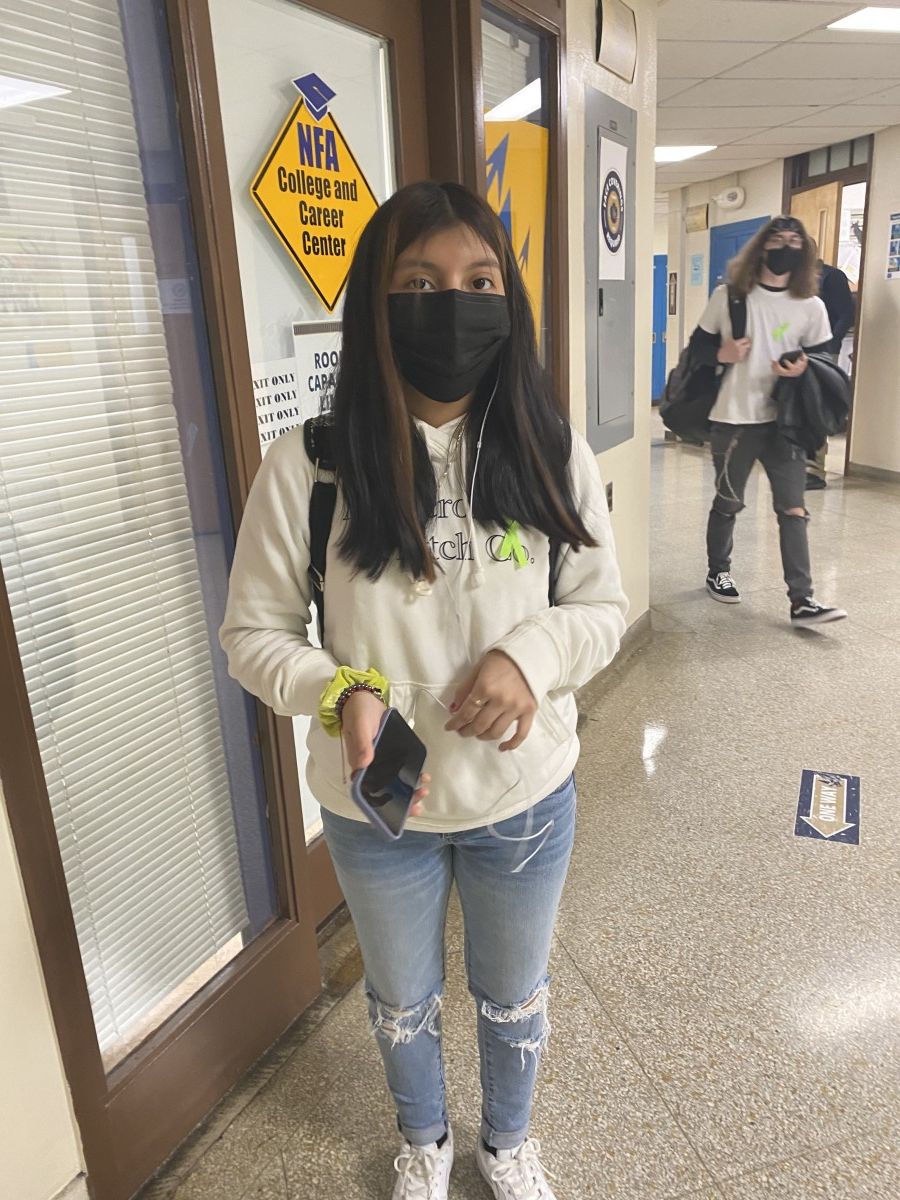 Student poses for a photo while wearing green ribbon to symbolize Mental Health Awareness Month.