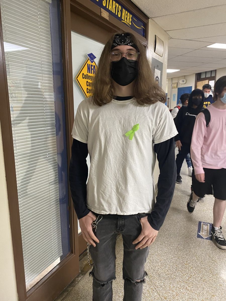 Student poses for a photo while wearing green ribbon to symbolize Mental Health Awareness Month.