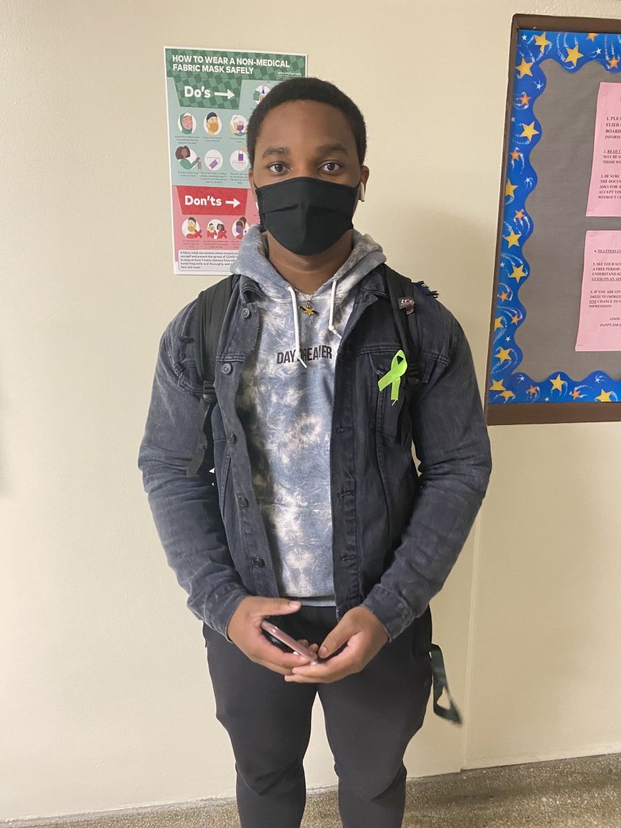 Student poses for a photo while wearing green ribbon to symbolize Mental Health Awareness Month.