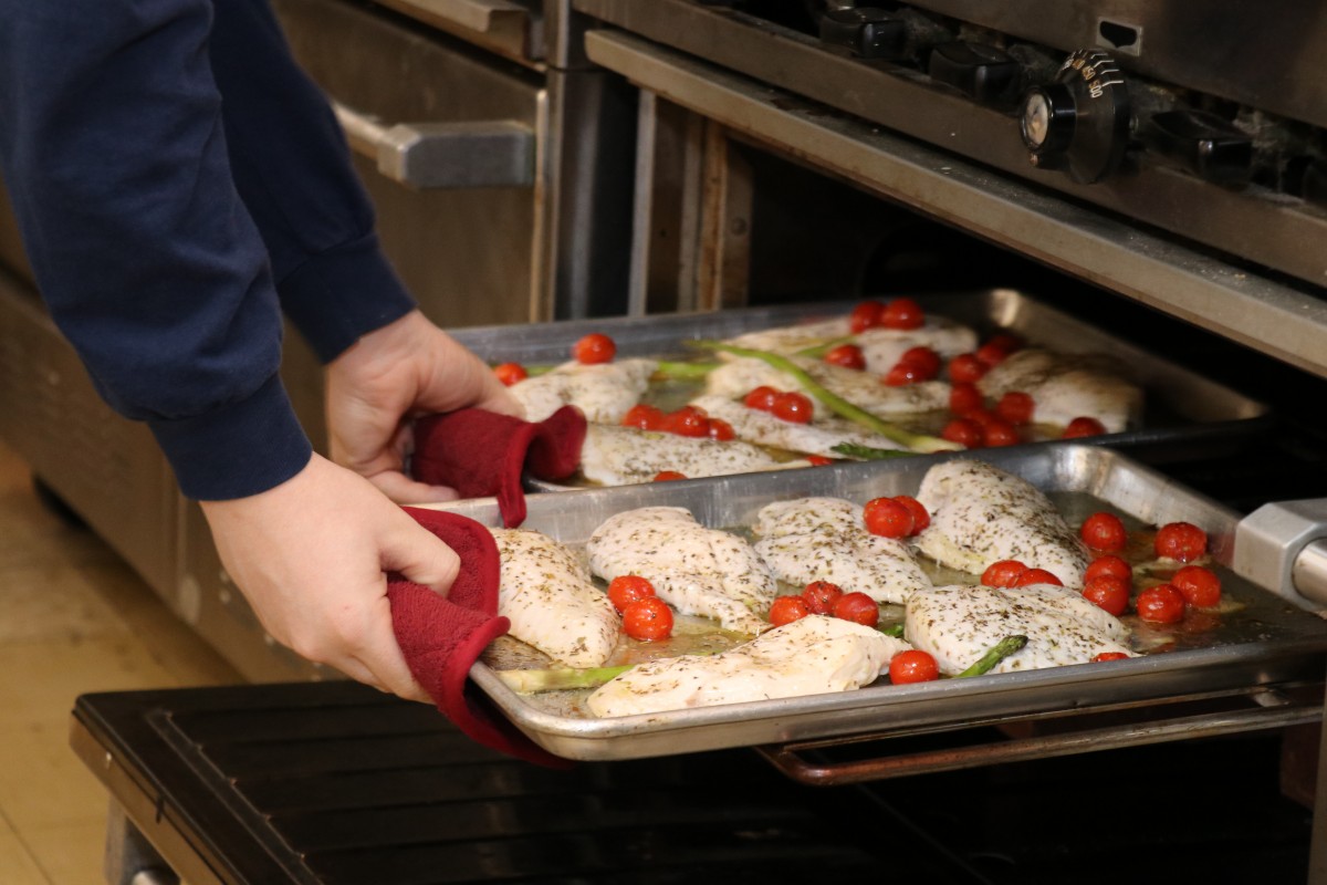 Students taking items out of the oven.