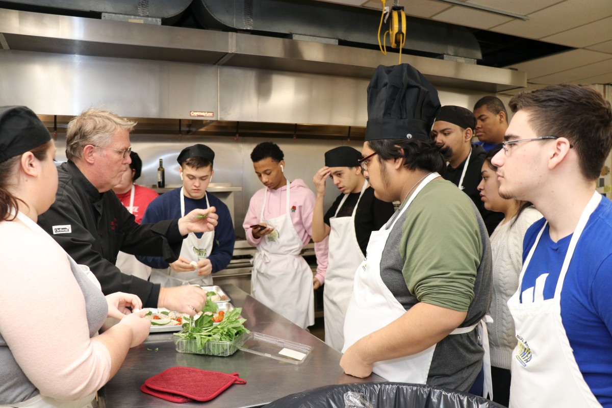 Chef instructs students during meal preparation.