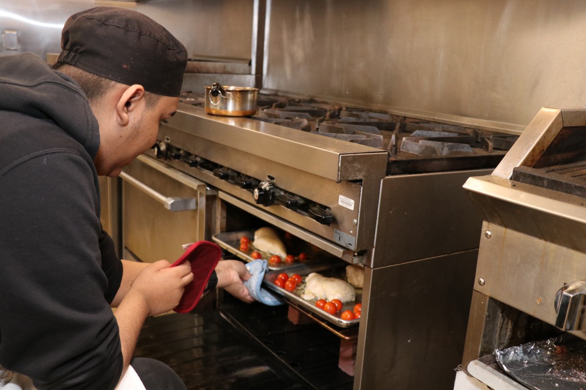 Students taking items out of the oven.