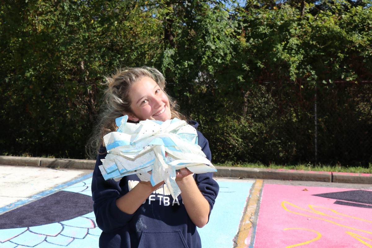 Student holds up ball of paint from painting parking spot.