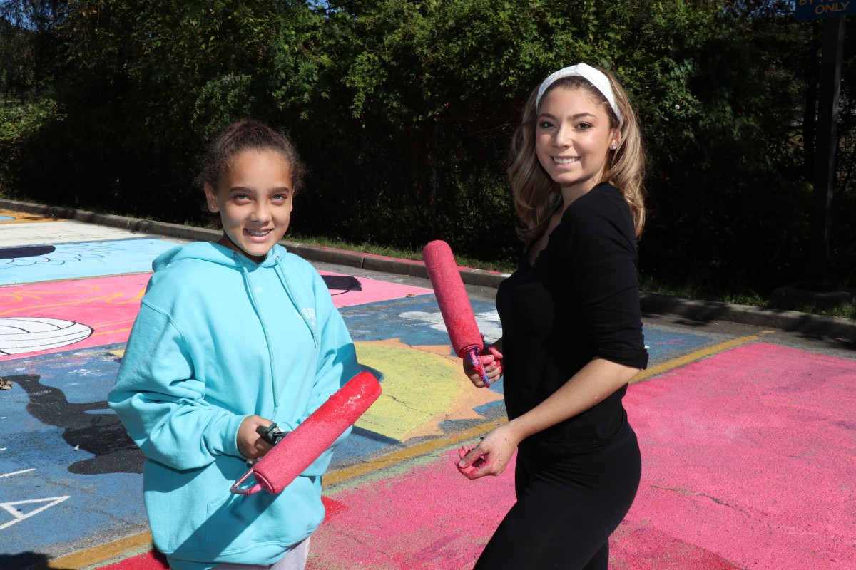 Students stand with painting equipment.